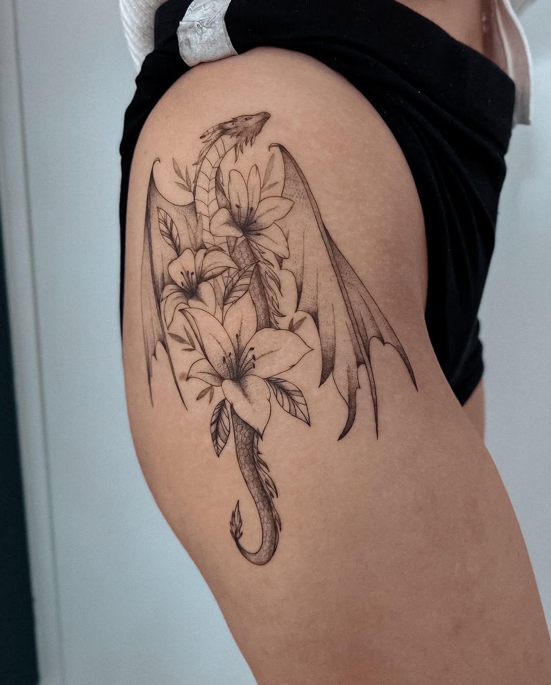 Elegant dragon intertwining flowers on thigh