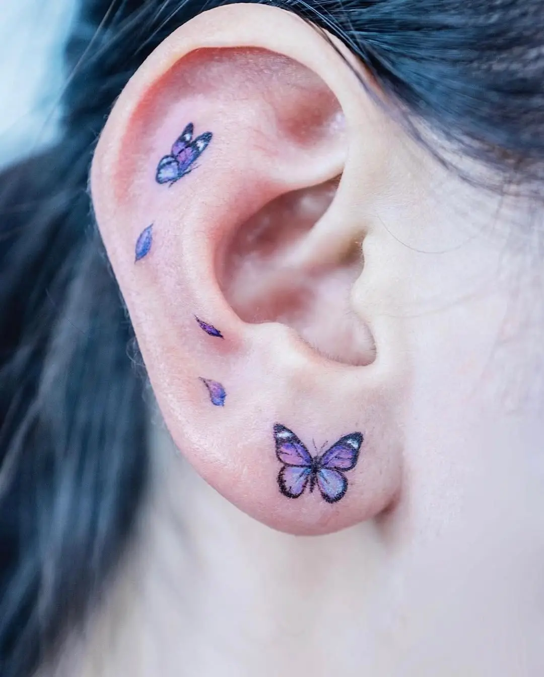 Vibrant butterfly tattoos adorning the ear