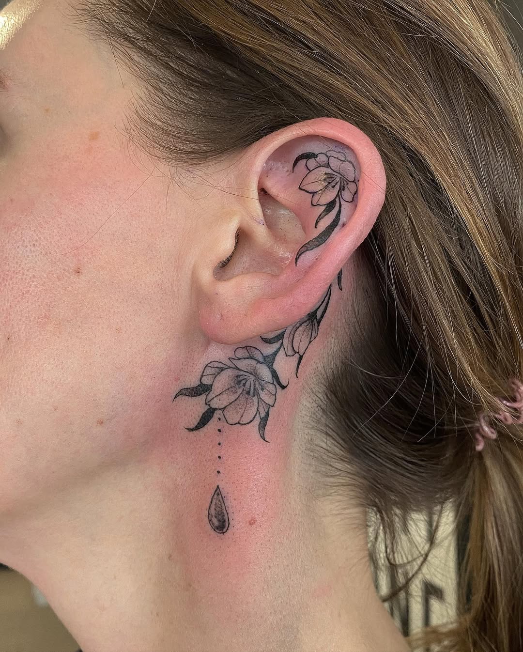 Elegant floral ear tattoo with droplet detail