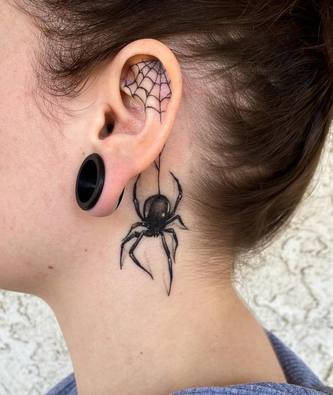 Intricate spider web tattoo behind the ear