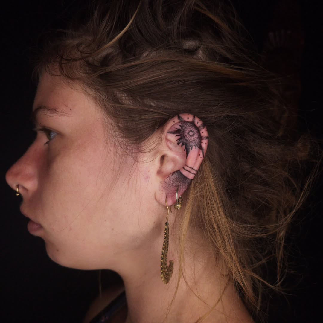 Stylish sun tattoo gracing the ear