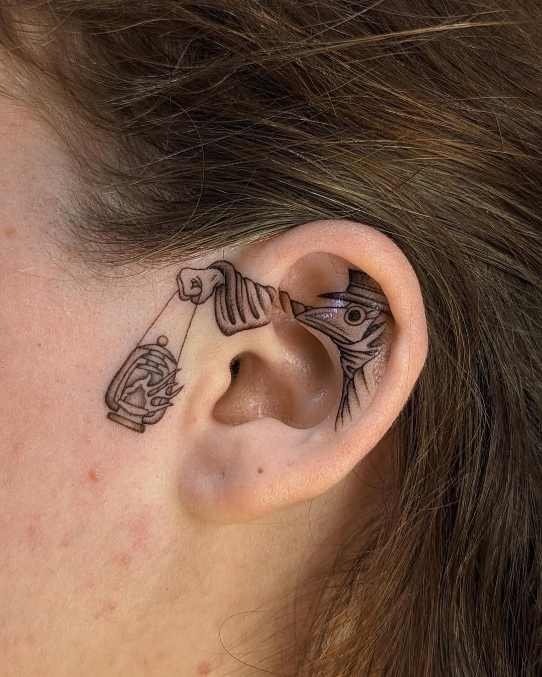 A whimsical fish-catching tattoo inside an ear