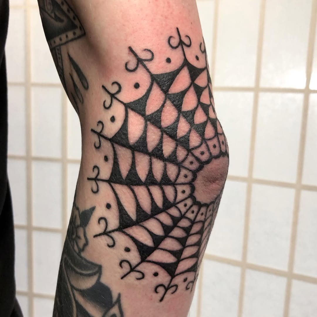 Intricate spider web design on elbow tattoo