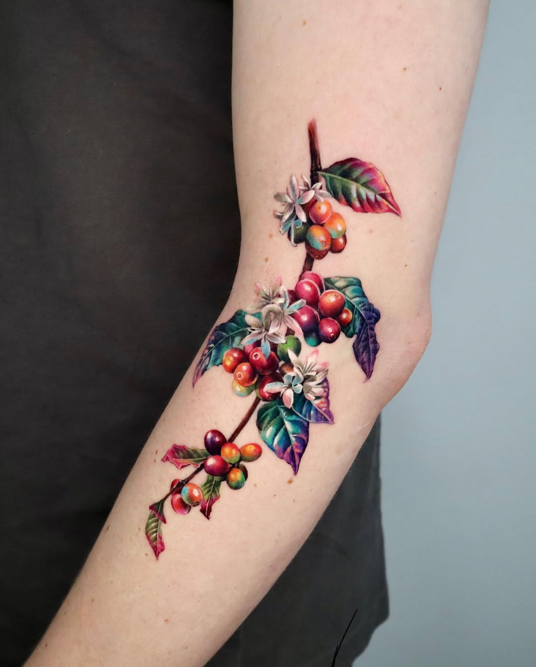 Vibrant botanical elbow tattoo showcasing nature's beauty