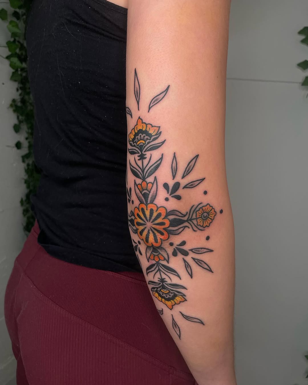 Vibrant floral elbow tattoo with bold outlines