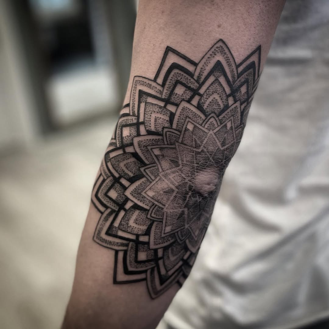 Intricate mandala elbow tattoo in black ink