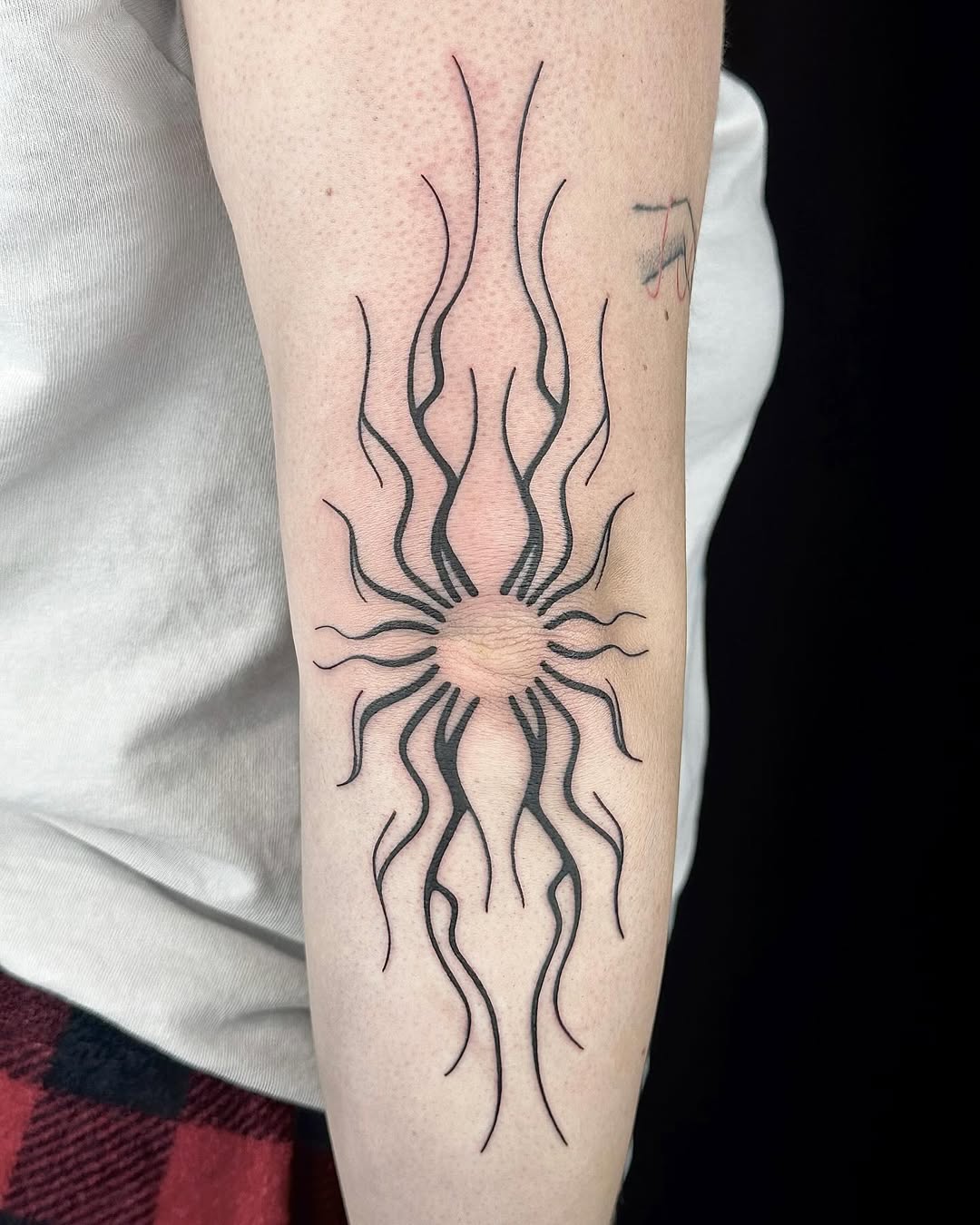 Stylish sunburst elbow tattoo with sharp lines