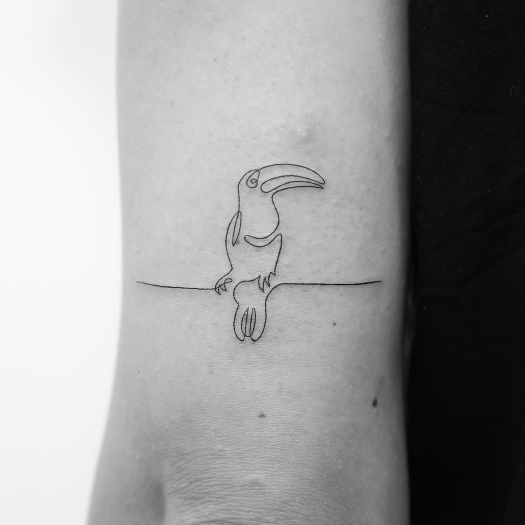 Minimalist toucan design on elbow tattoo