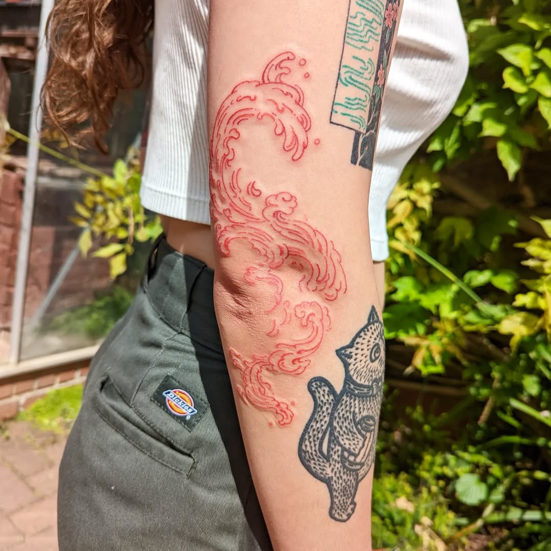 Stunning red wave design with fish tattoo