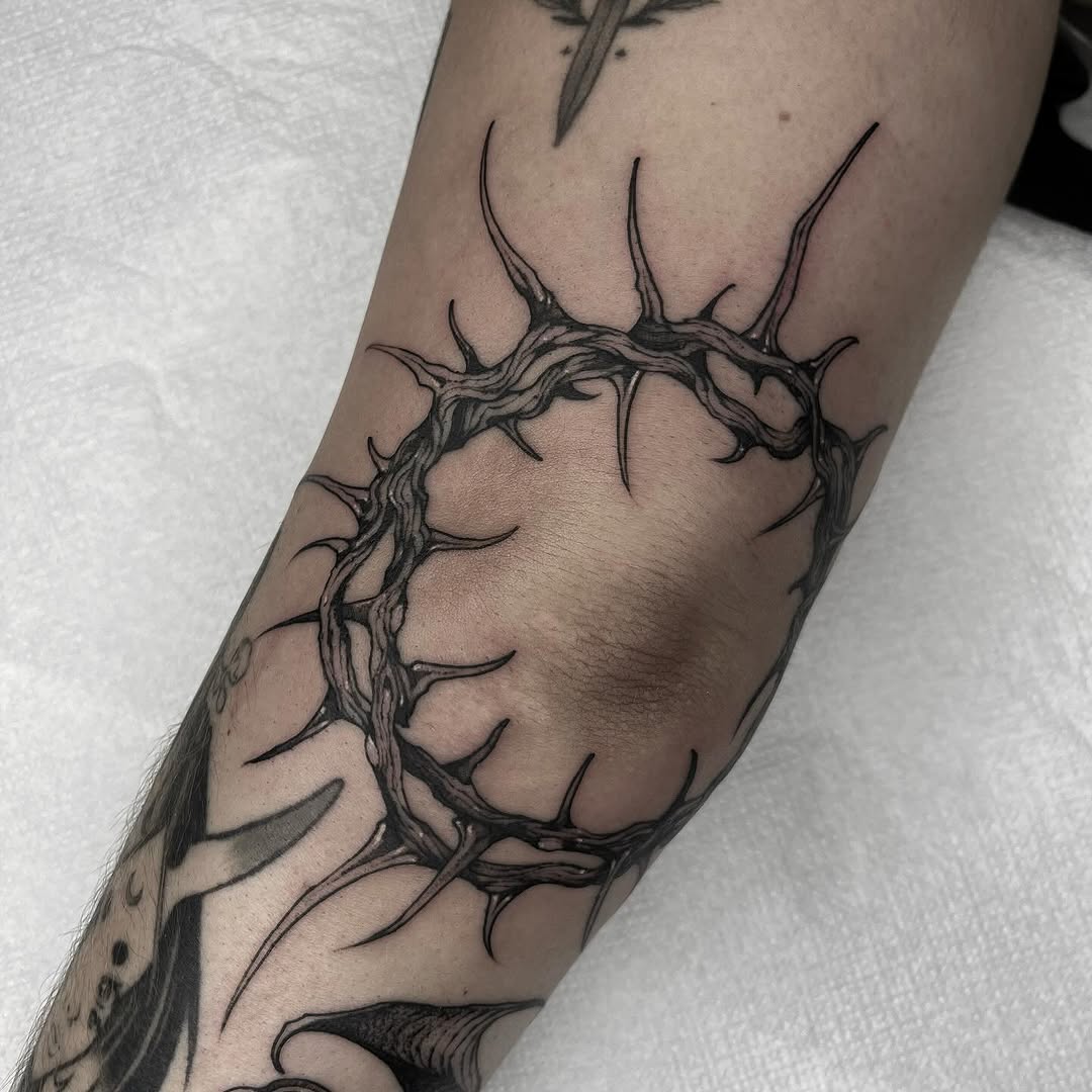 Intricate thorned circle tattoo on elbow