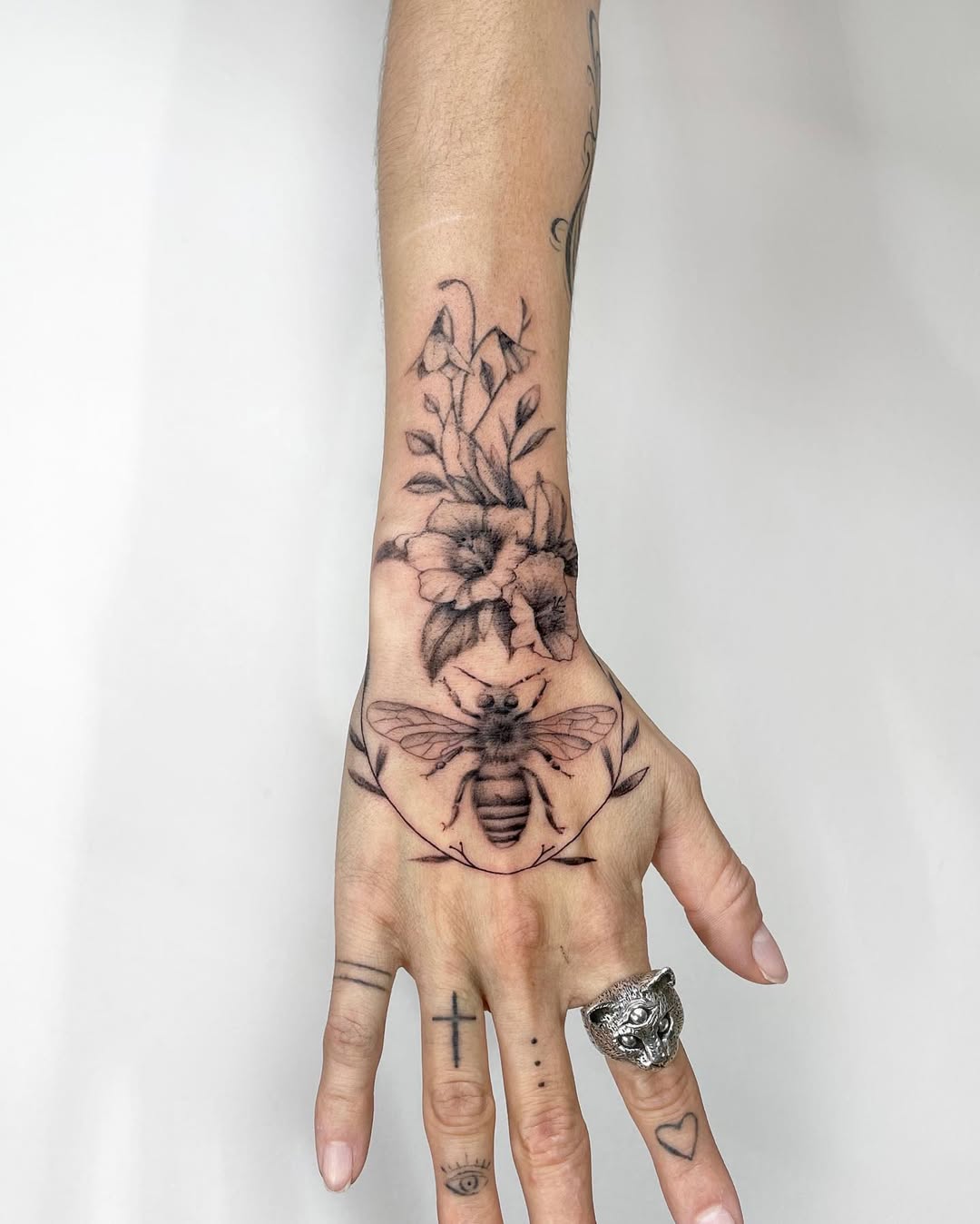 Elegant floral-themed bee tattoo on hand