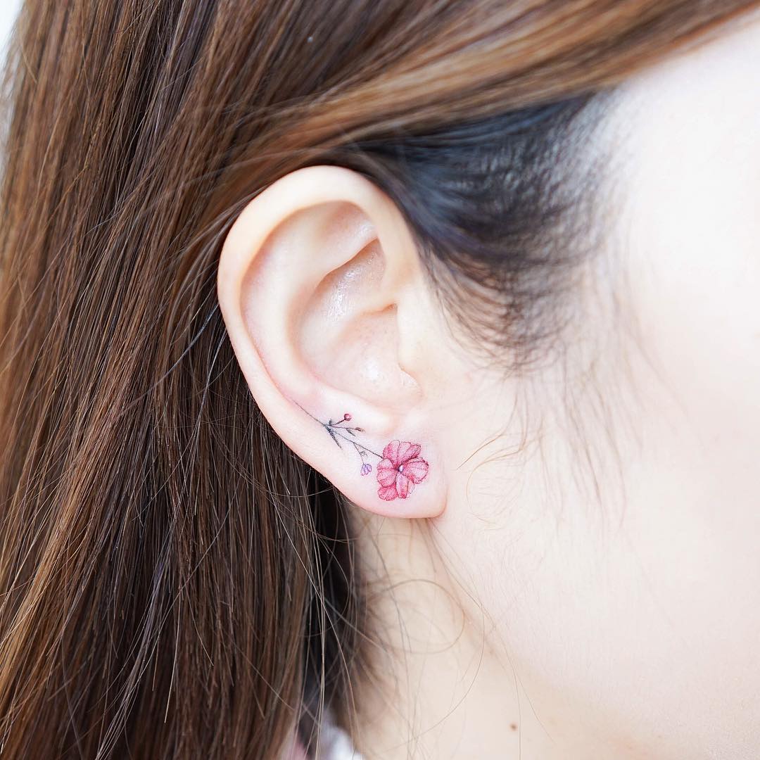 Delicate flower tattoo on ear adds charm