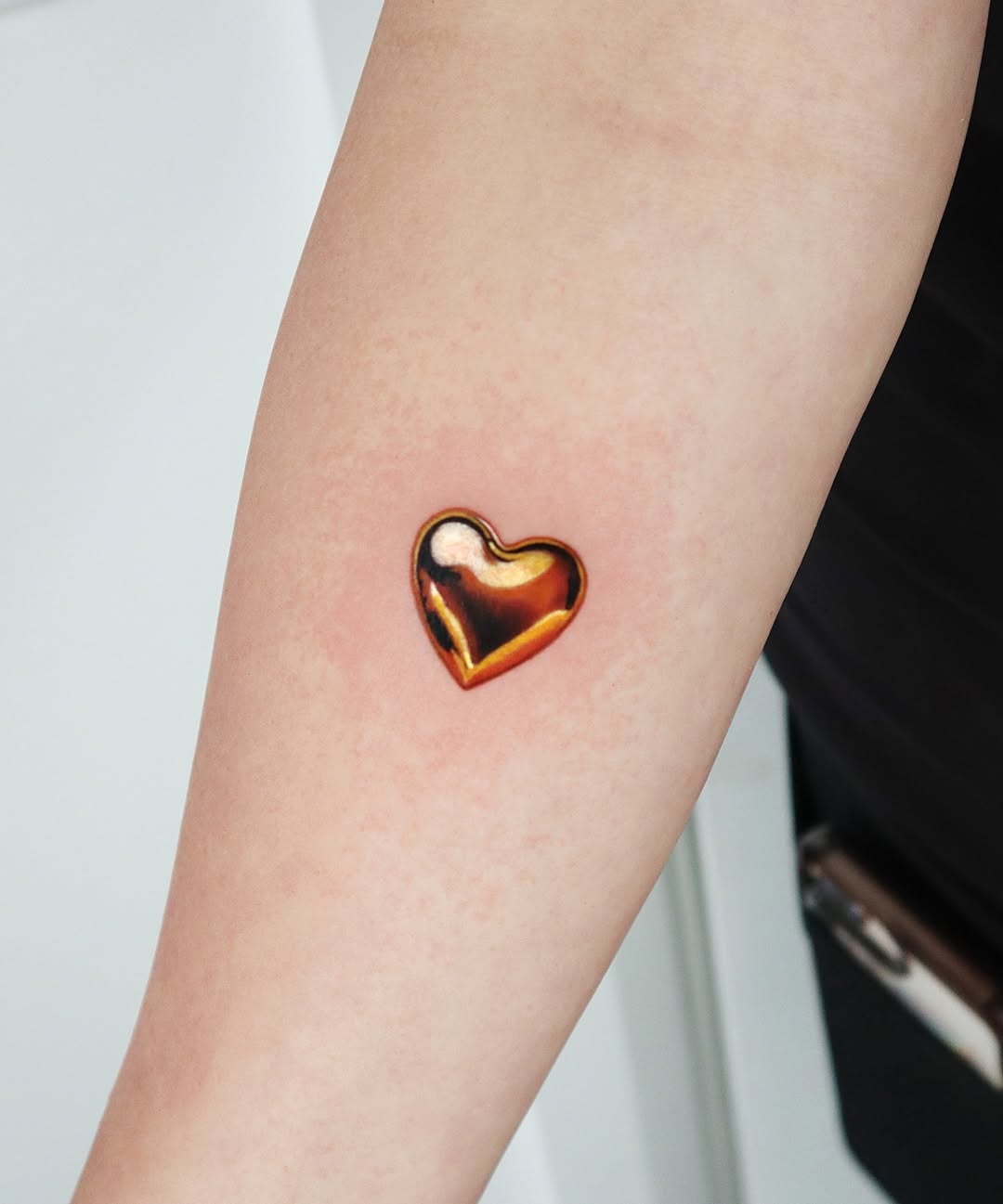 Glossy finish heart tattoo on forearm