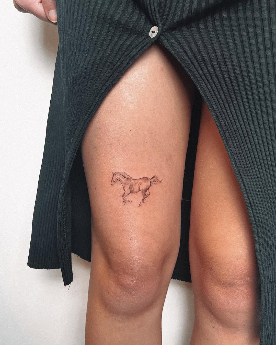 Elegant minimalist horse tattoo on thigh