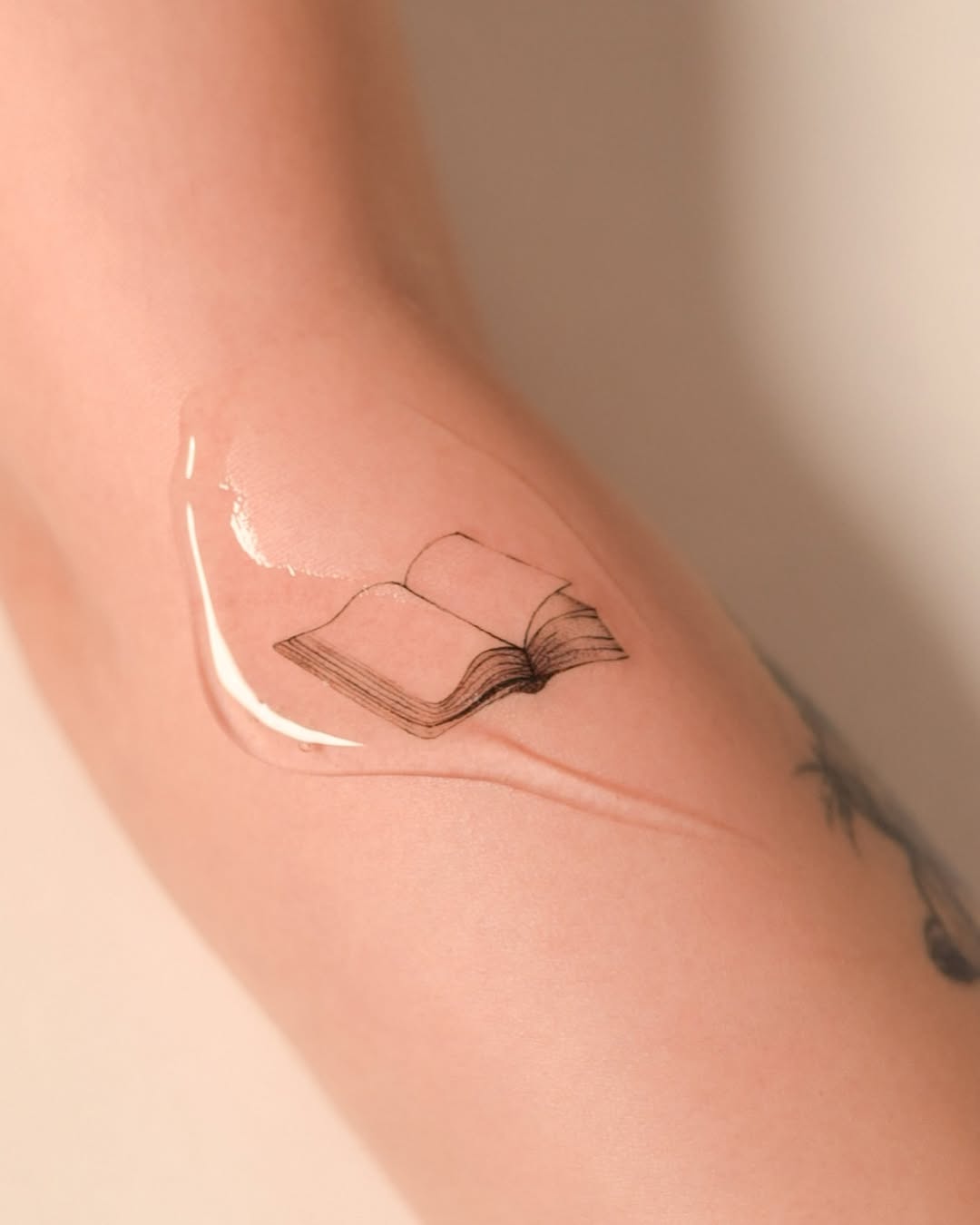 Elegant minimalist book tattoo on forearm