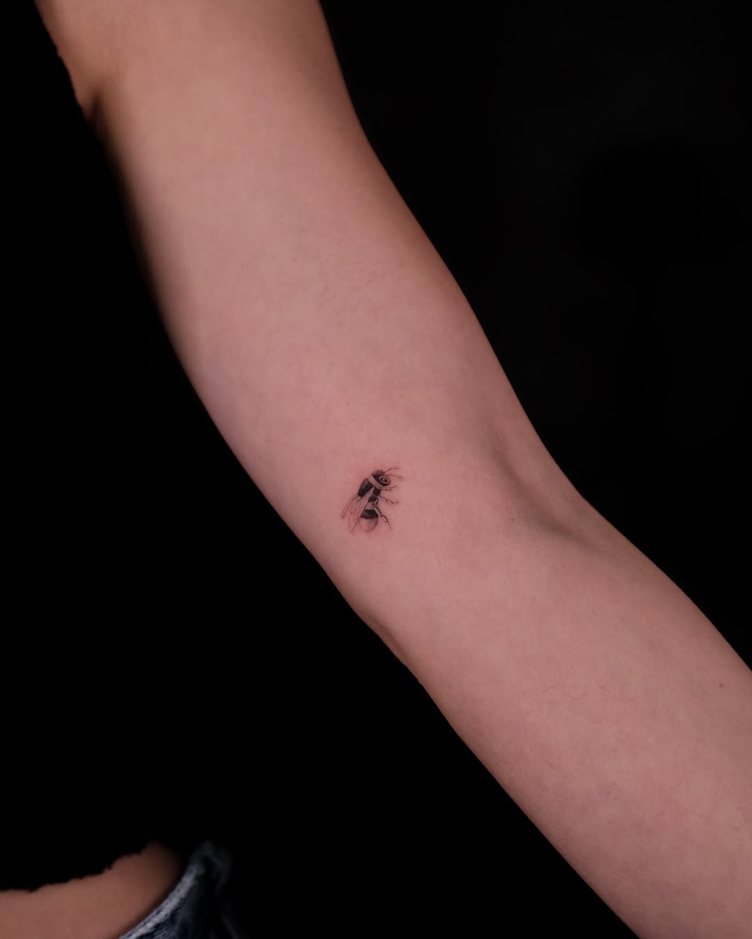 Stylish minimalist bee tattoo on the arm