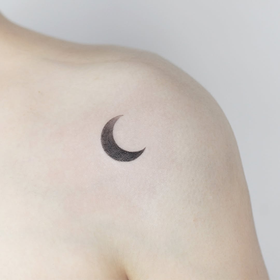 Delicate crescent moon tattoo on shoulder