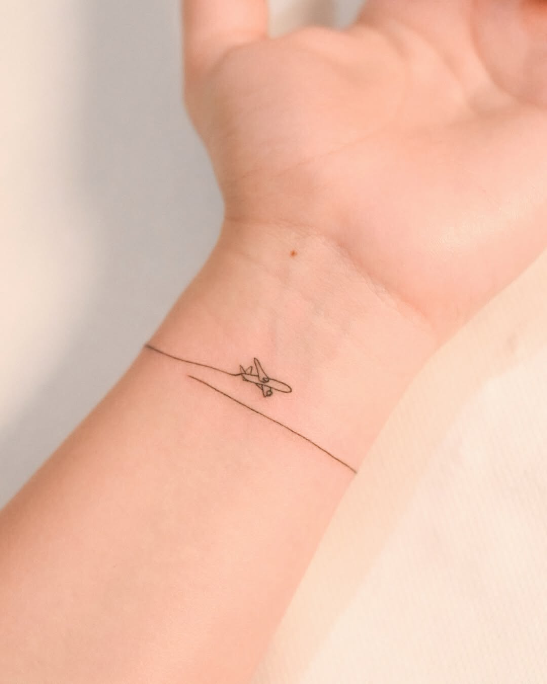 Minimalist airplane tattoo on the wrist