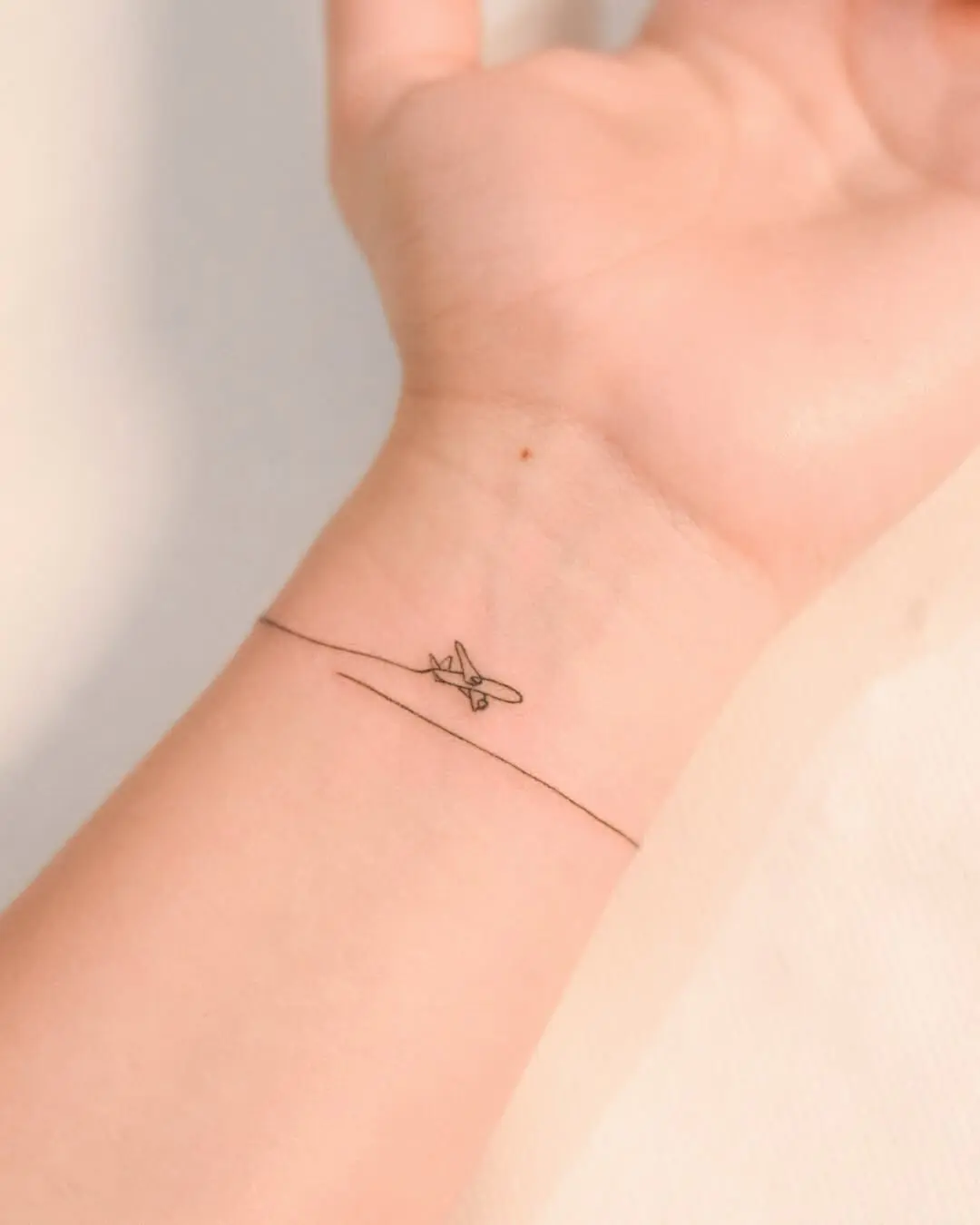 Minimalist airplane tattoo on the wrist