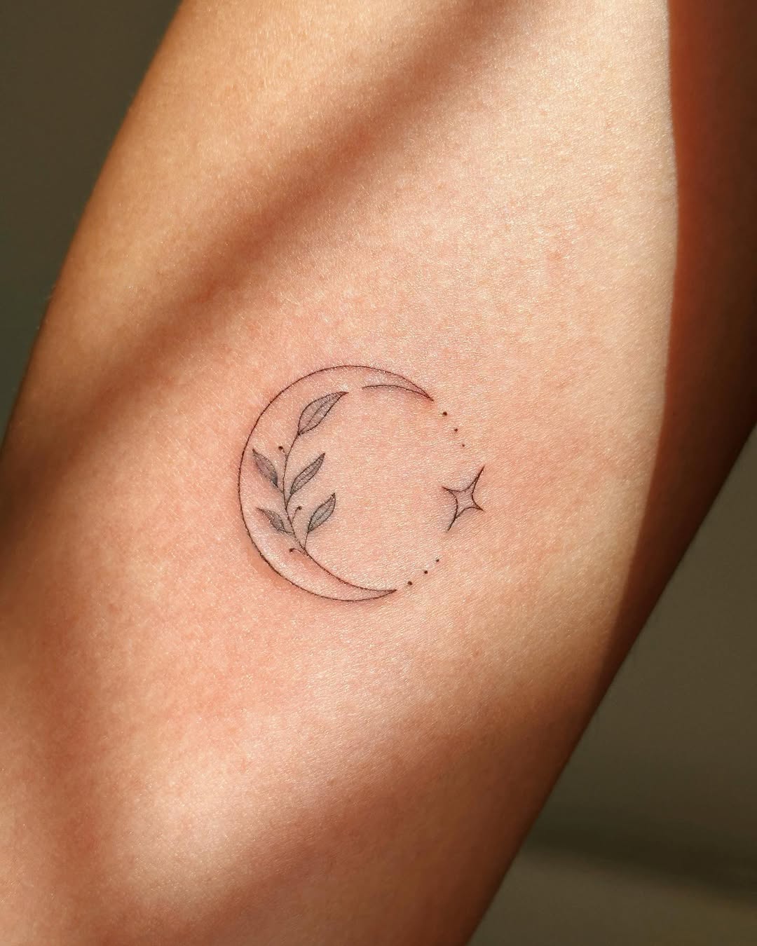 Elegant moon tattoo with delicate foliage.