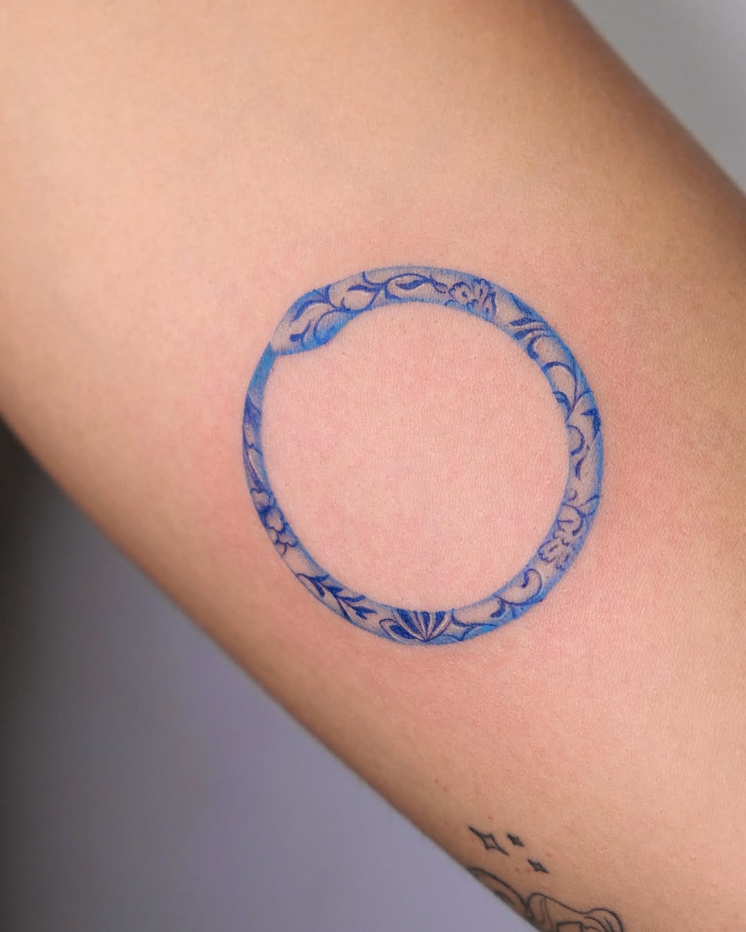 Elegant blue ouroboros tattoo with floral motifs