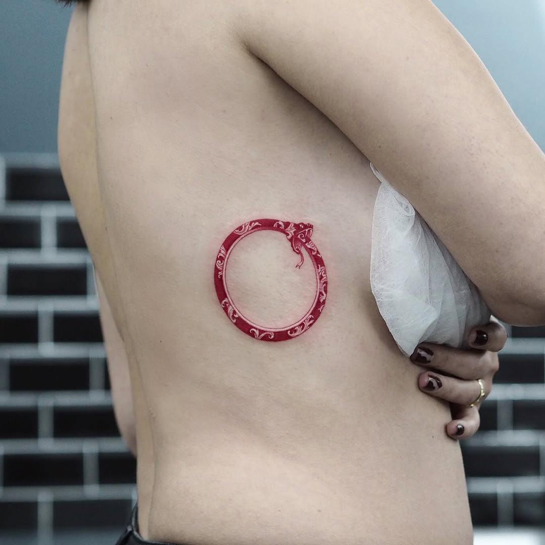 Striking red ouroboros tattoo on skin