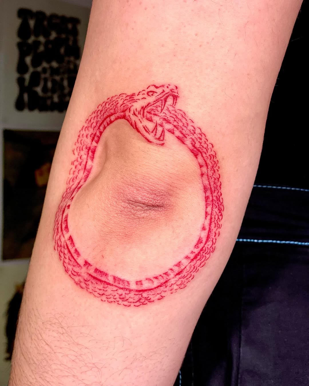 Intricate red ouroboros tattoo on the arm