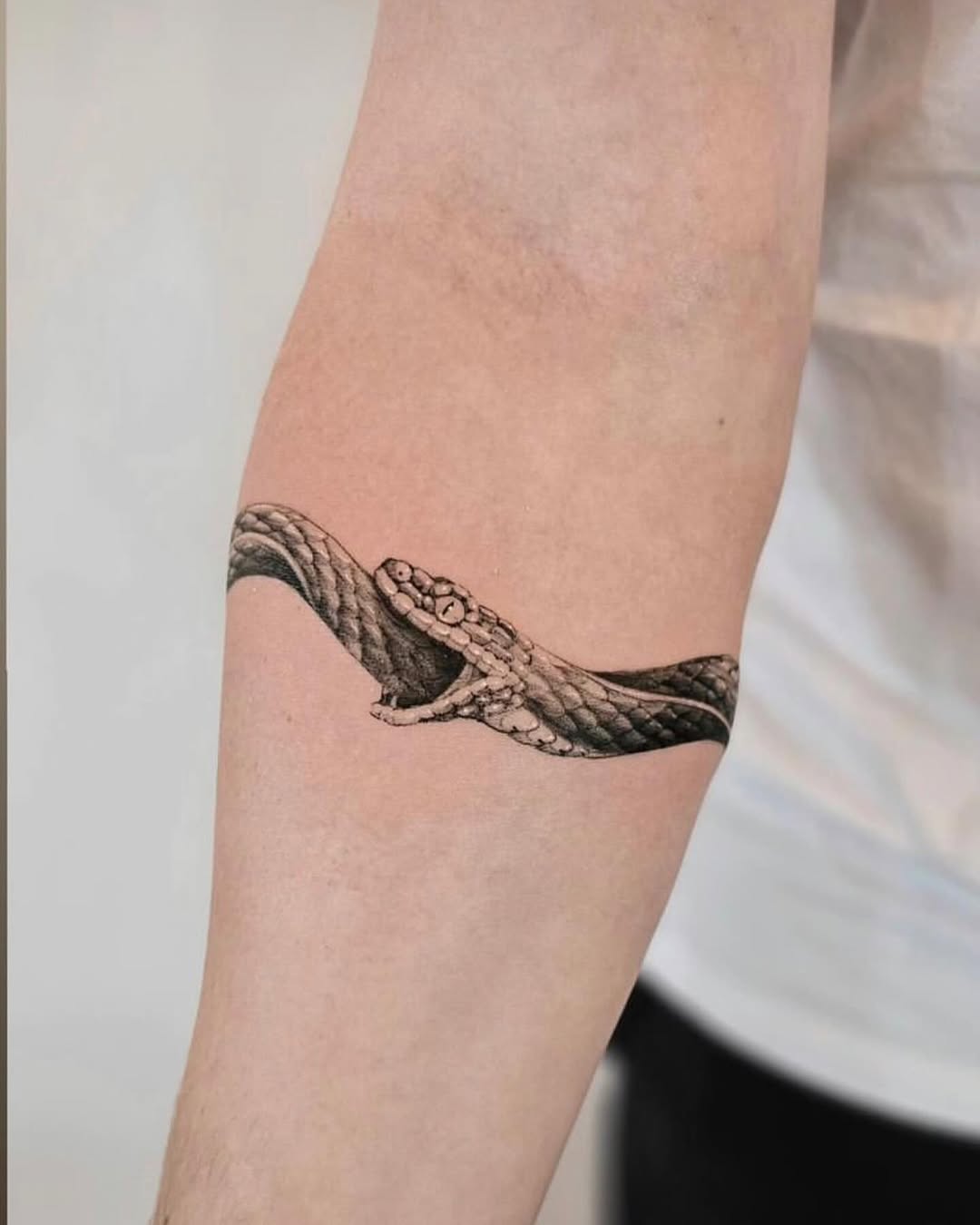 Intricate ouroboros tattoo wrapped around arm