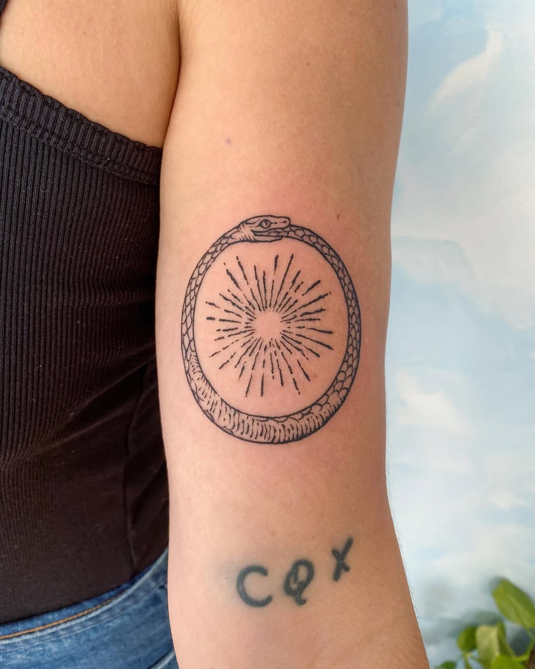 A mesmerizing ouroboros tattoo with sun rays