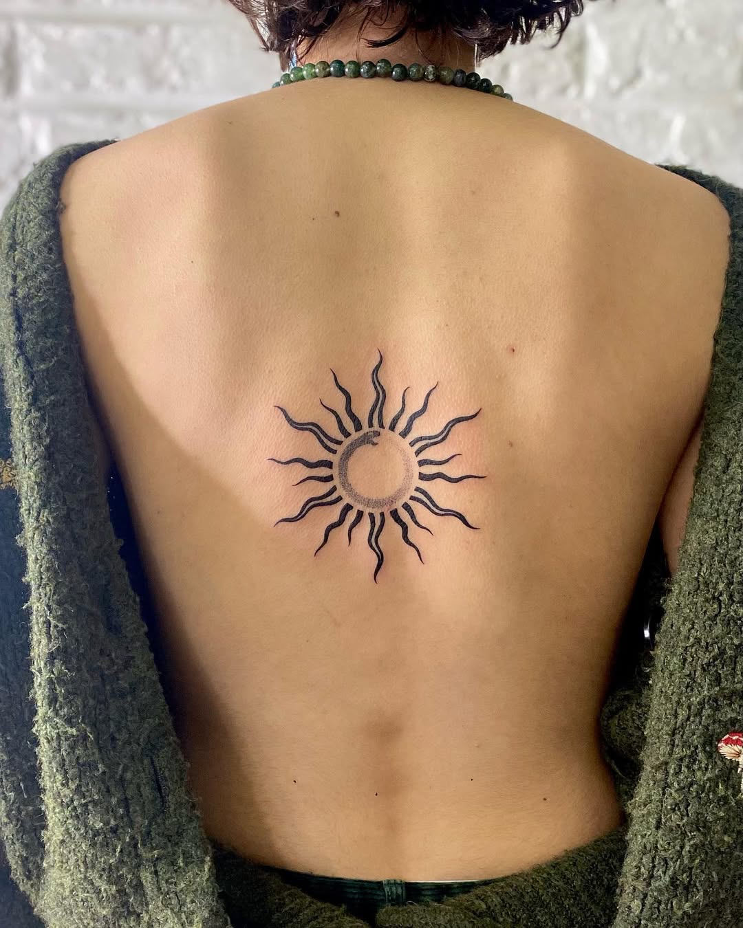 Symbolic sun design in minimalist tattoo art