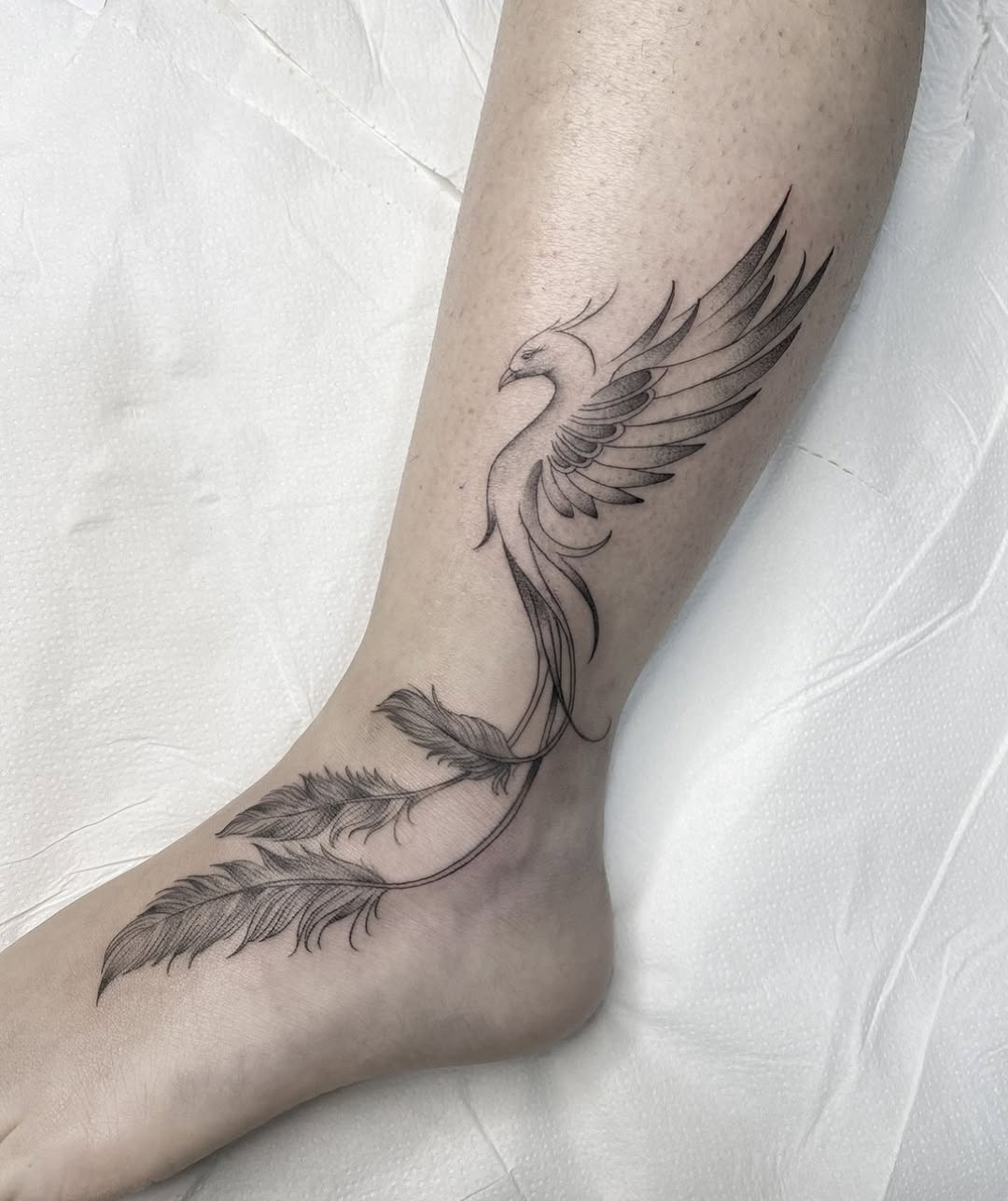 Elegant black phoenix tattoo with feather details.