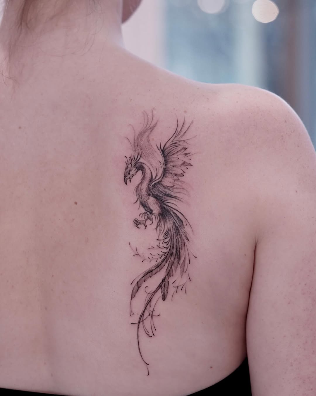 Elegant phoenix tattoo soaring on the back.