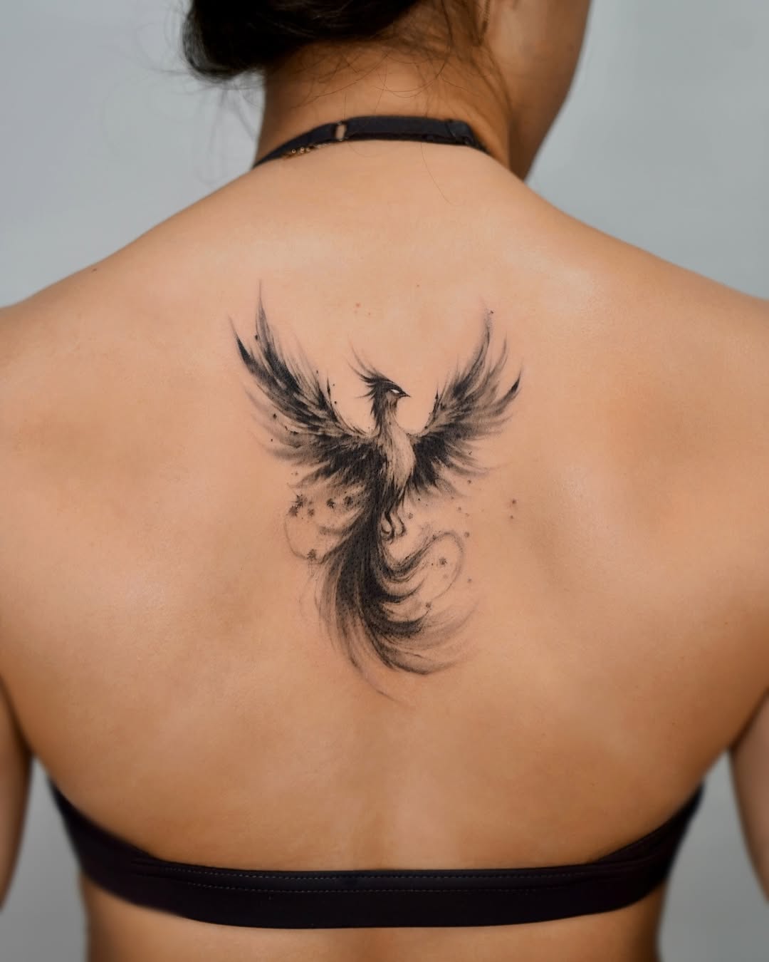 Stunning black ink phoenix tattoo on back