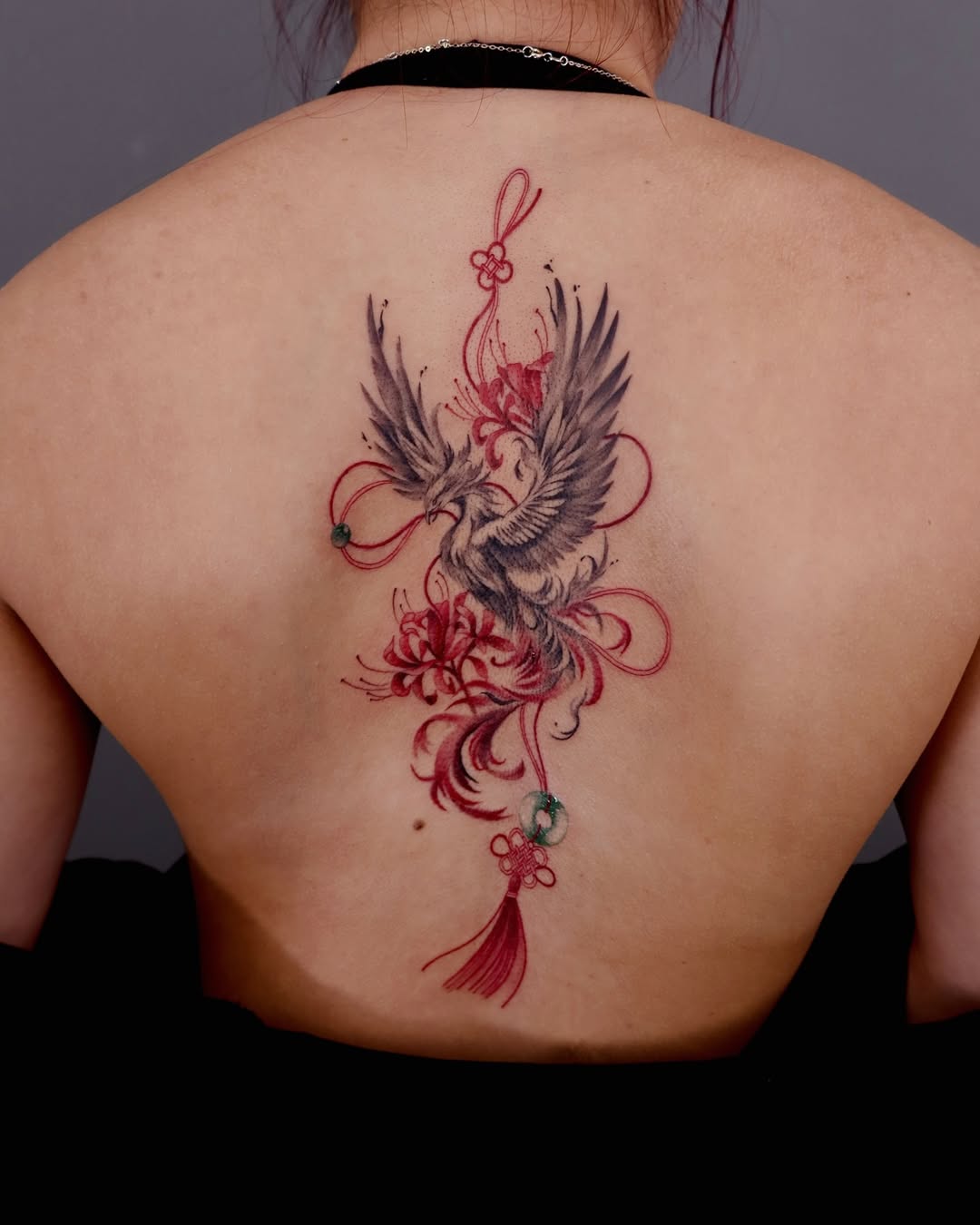 Elegant phoenix tattoo surrounded by floral motifs.