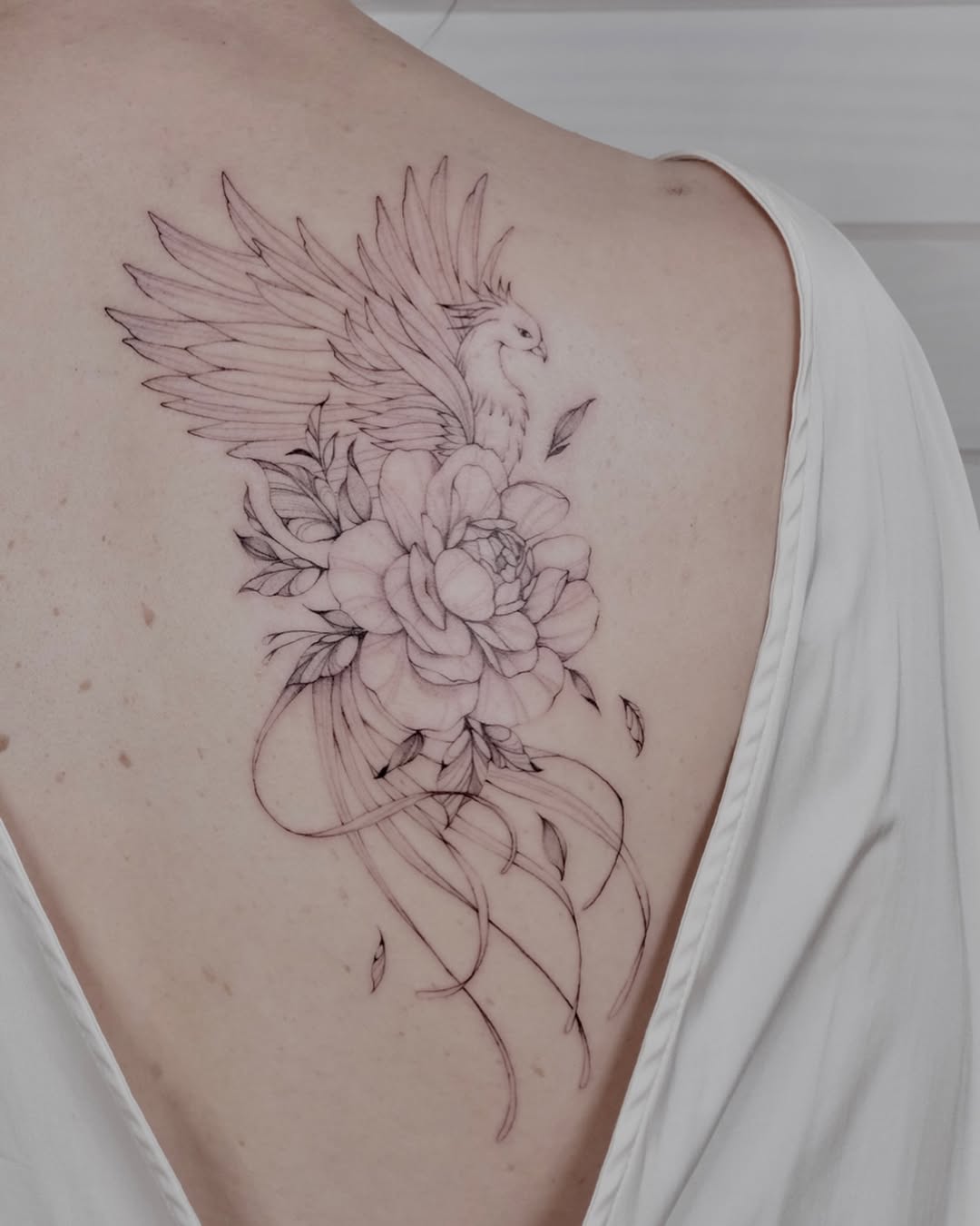 Elegant phoenix tattoo with floral details