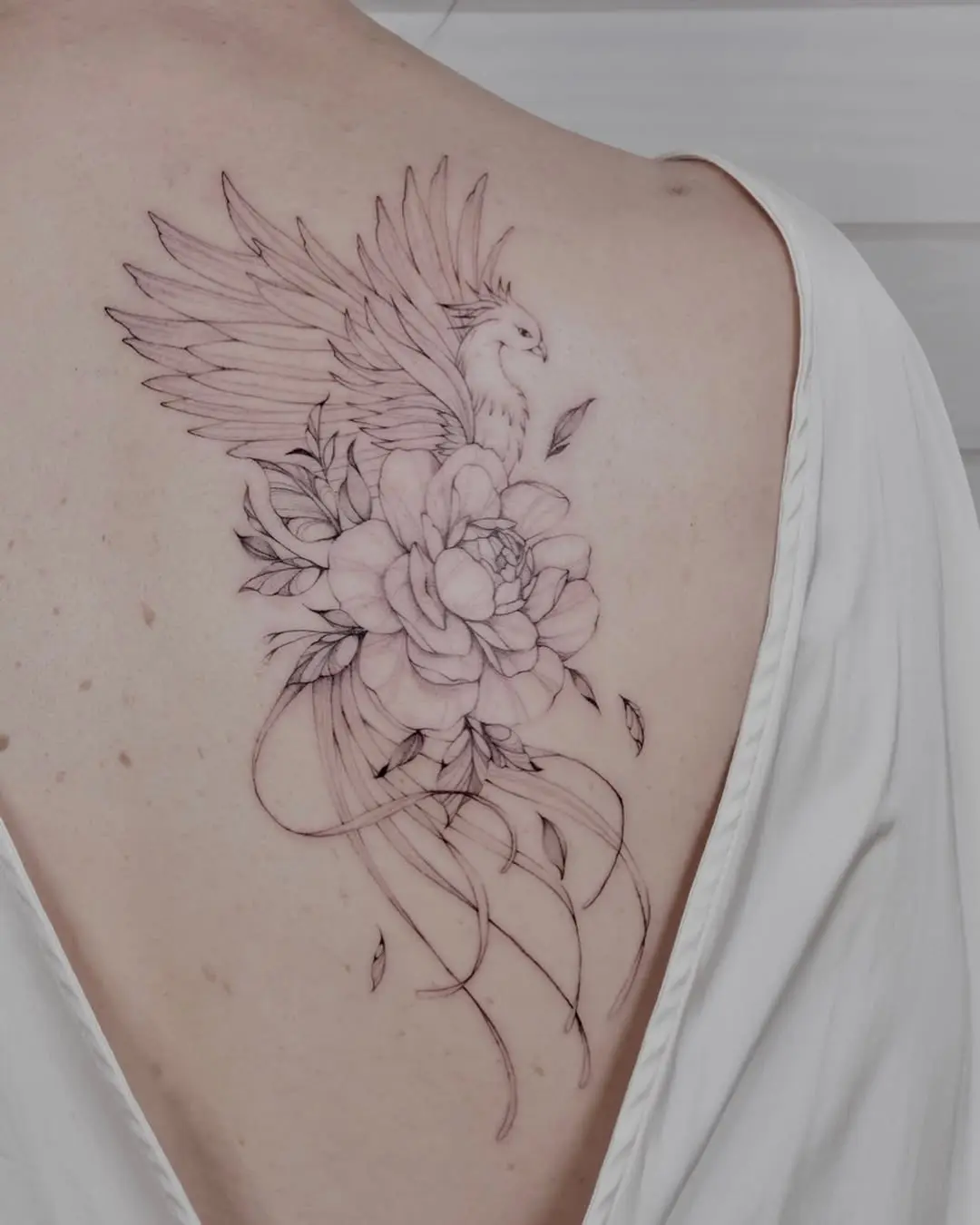 Elegant phoenix tattoo with floral details