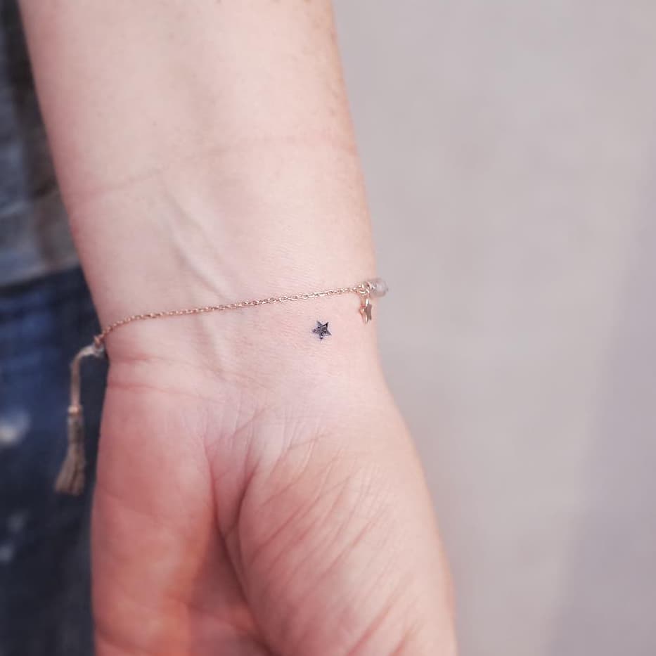 Minimalist star tattoo on wrist shines softly