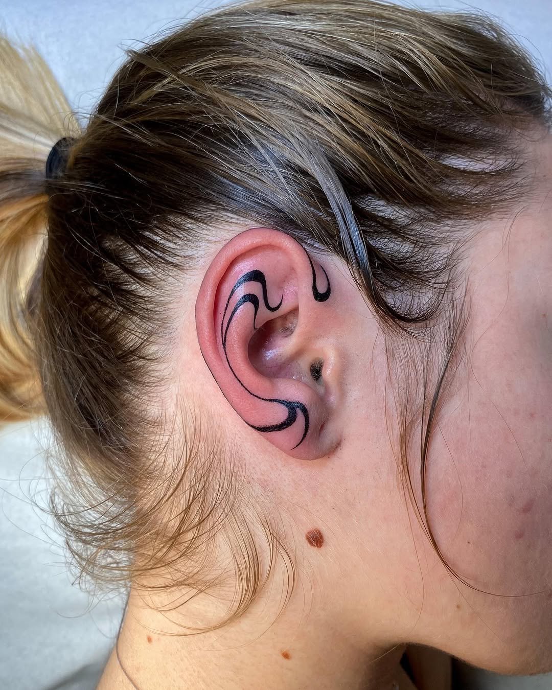 Elegant black line art tattoo on ear