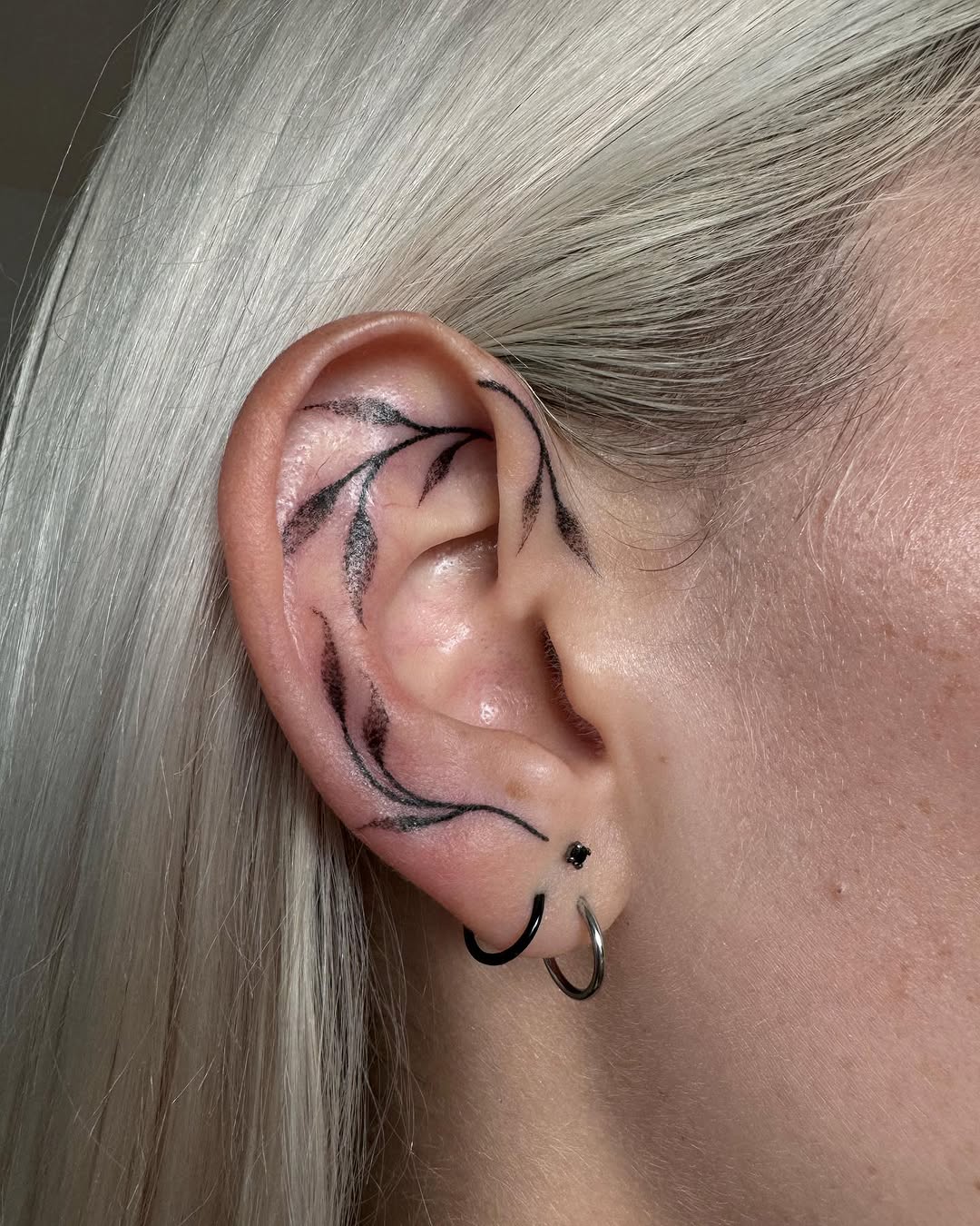 Elegant black line ear tattoo with floral motifs