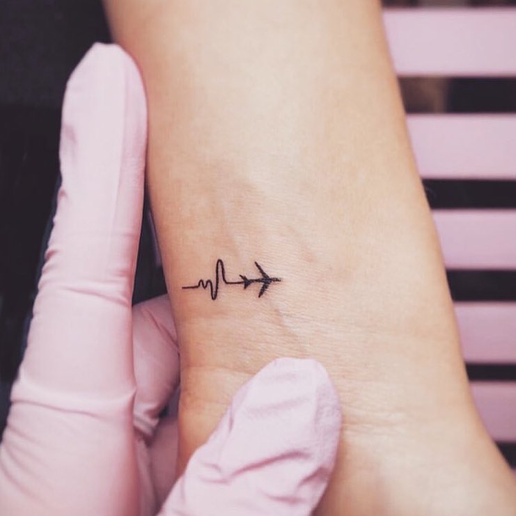 Symbolic travel tattoo blending heartbeat and airplane