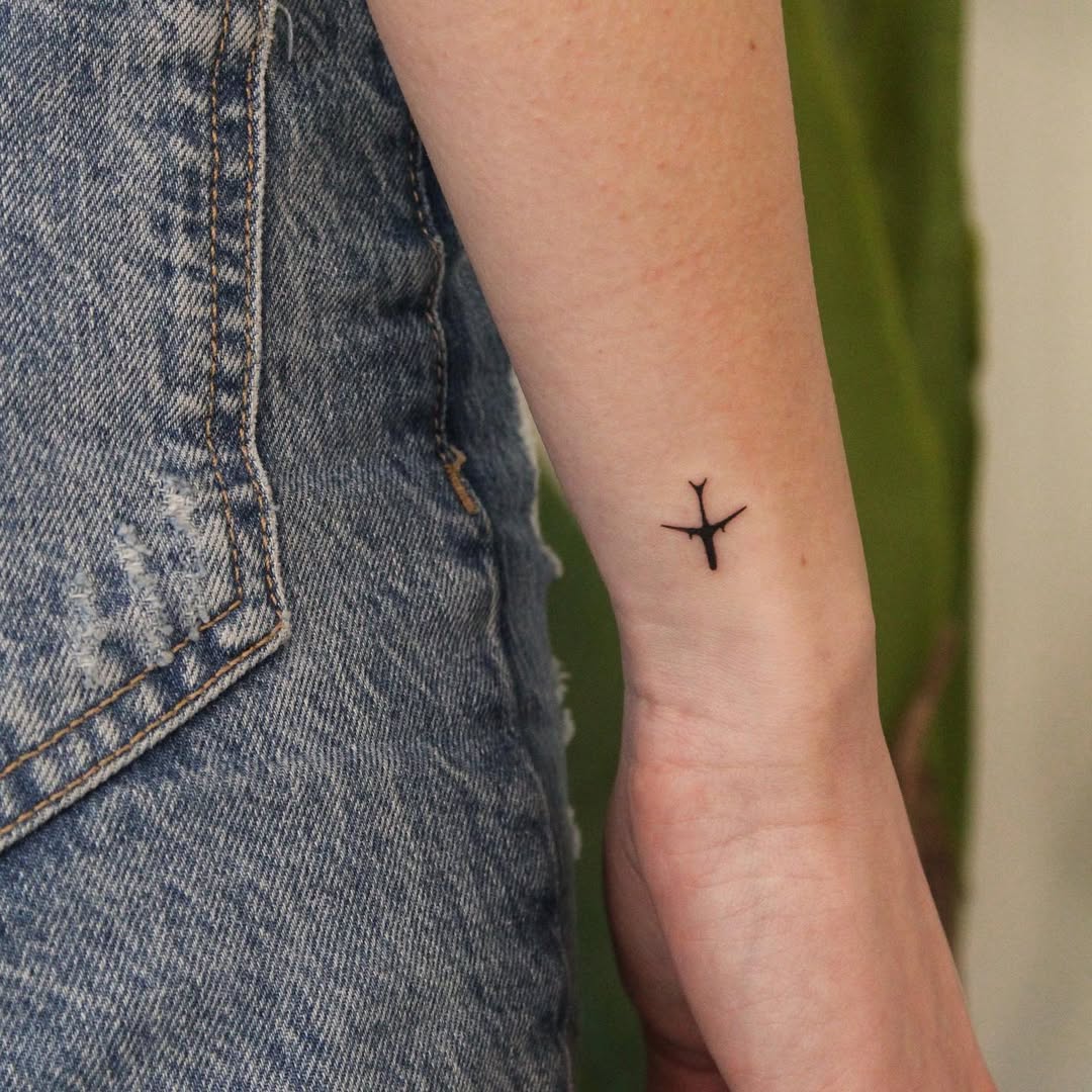 Minimalist airplane tattoo on the arm