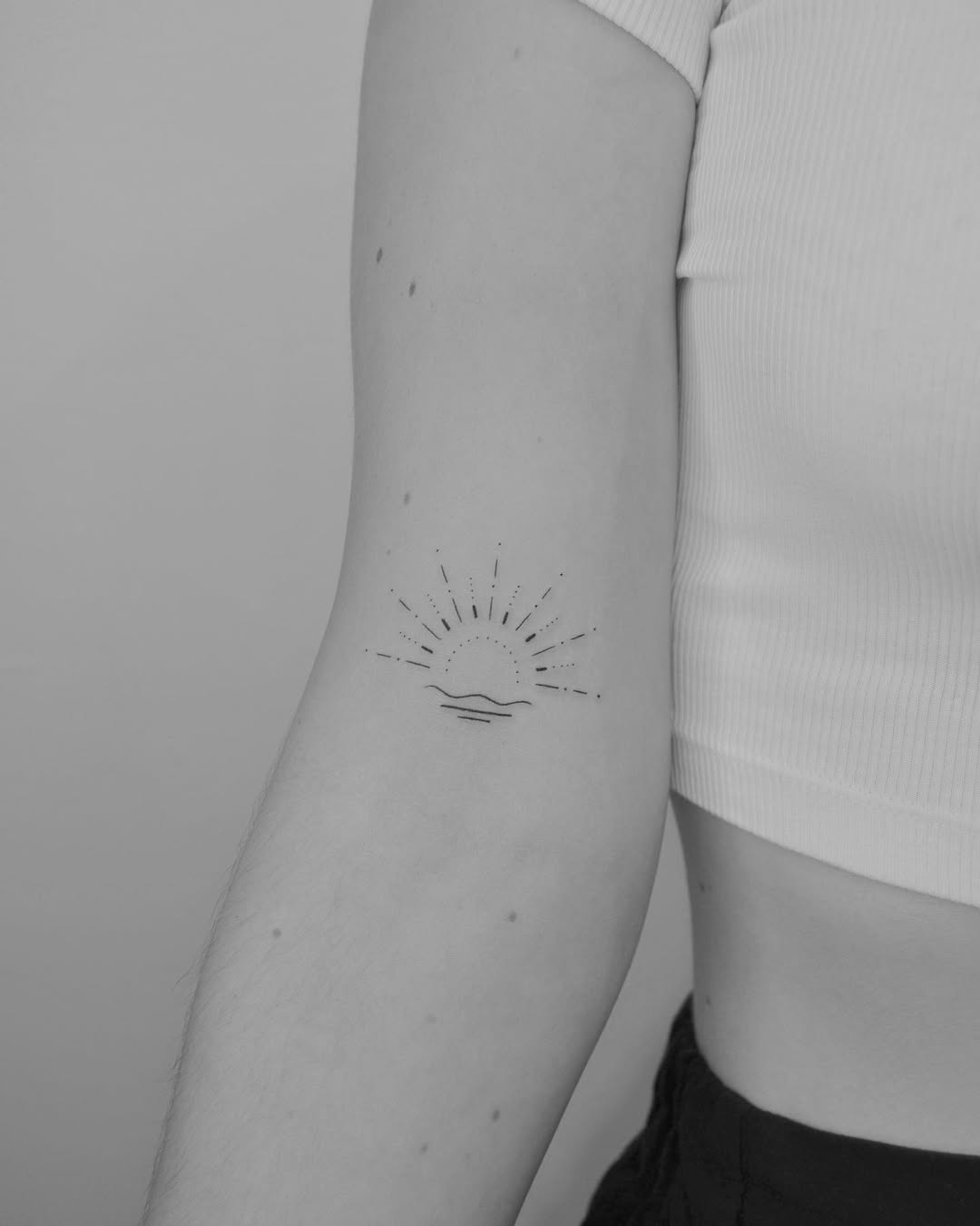 Minimalist sun tattoo radiating positivity