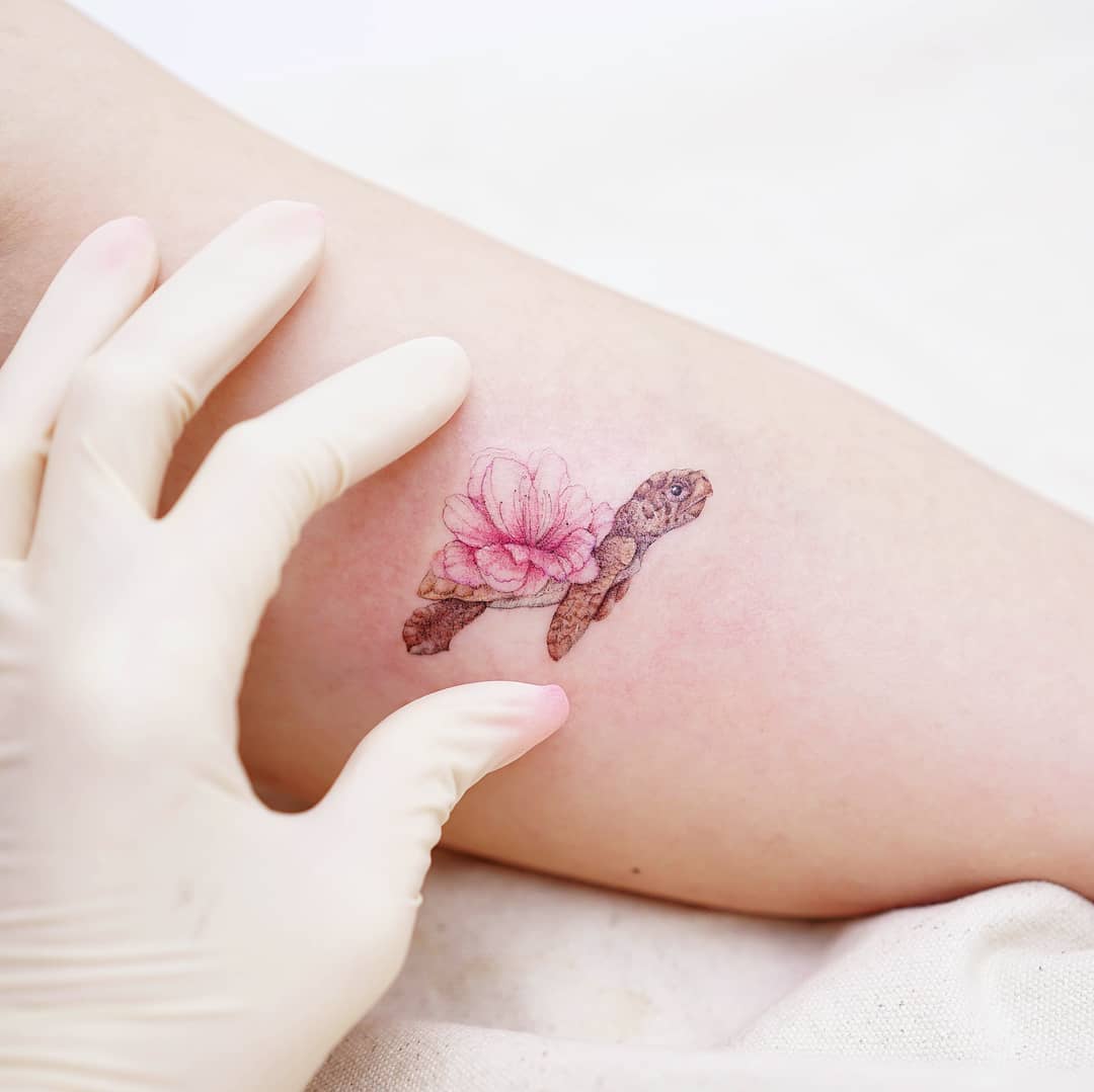 Delicate turtle tattoo with flower detailing