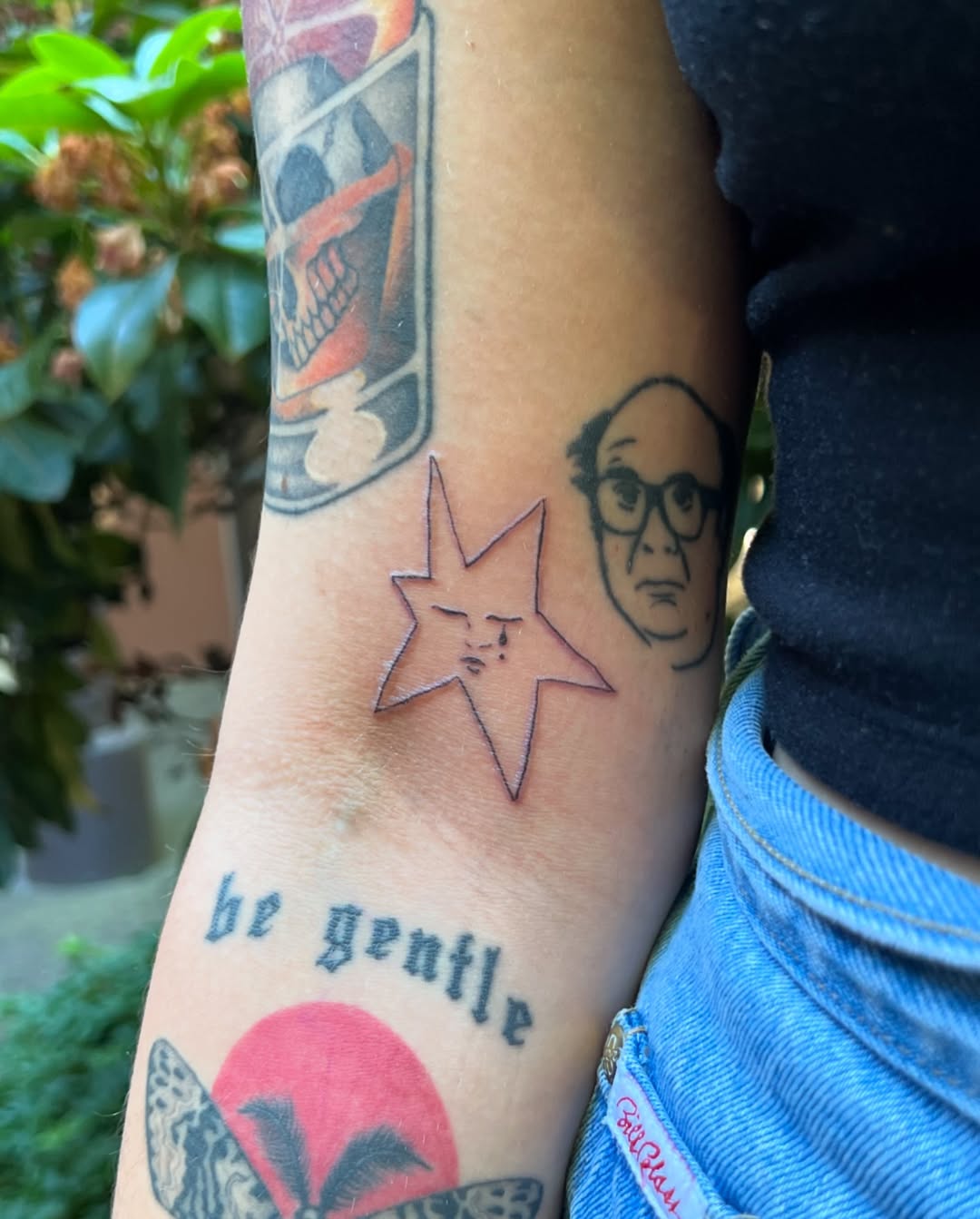 Quirky face-themed star tattoo on forearm