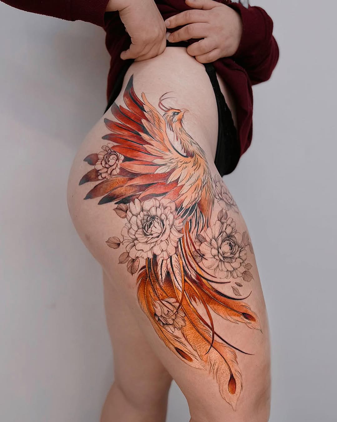 Stunning thigh phoenix tattoo with floral elements