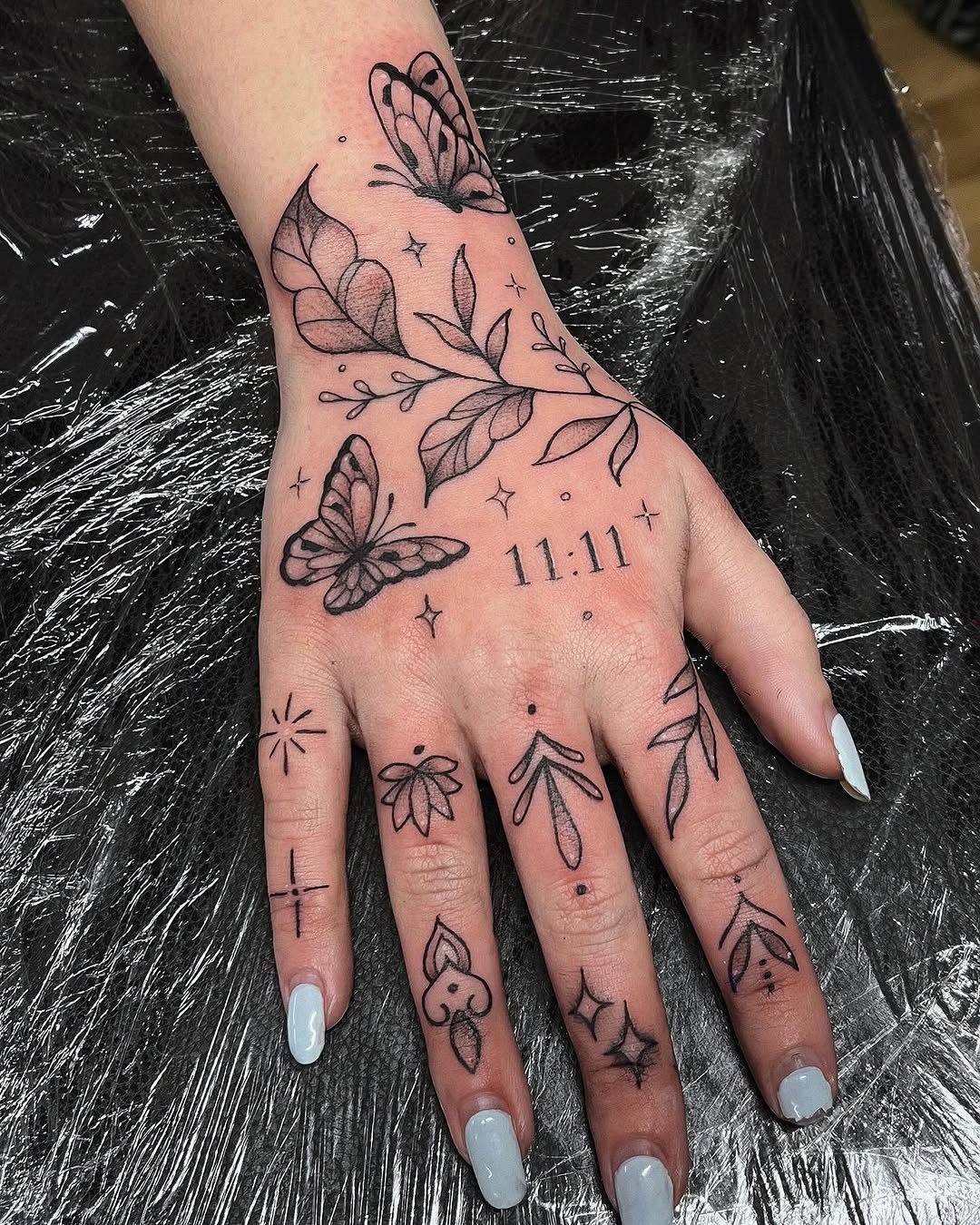 Elegant hand tattoo featuring butterflies and symbols