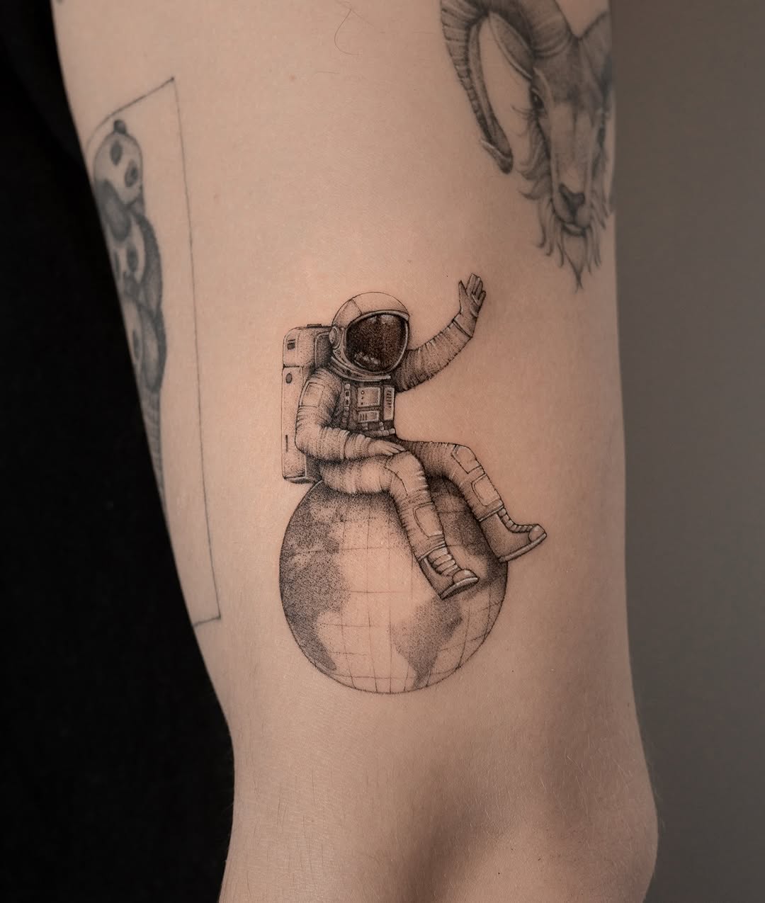 Charming astronaut tattoo resting on Earth