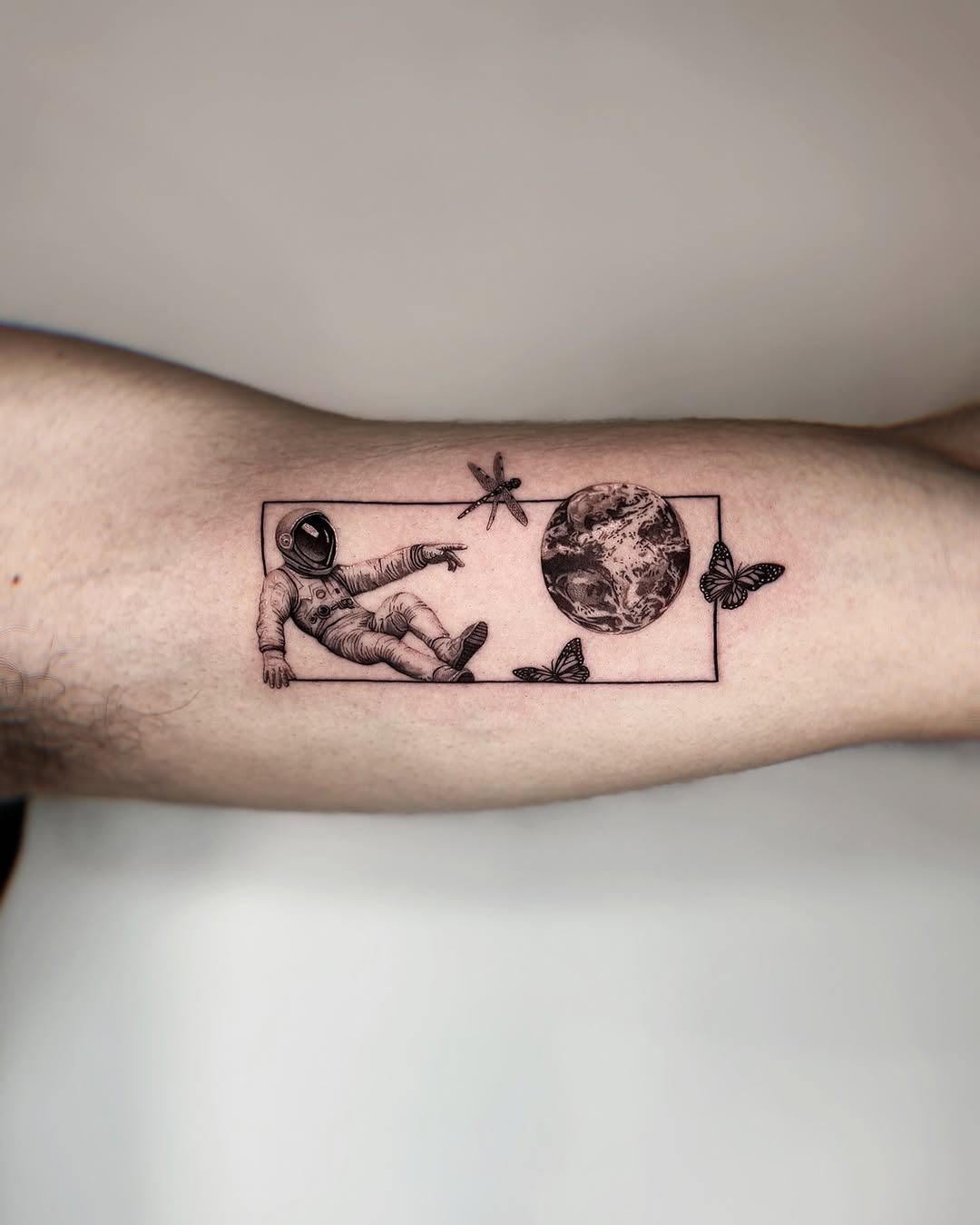 Stylish astronaut tattoo with butterflies and Earth.