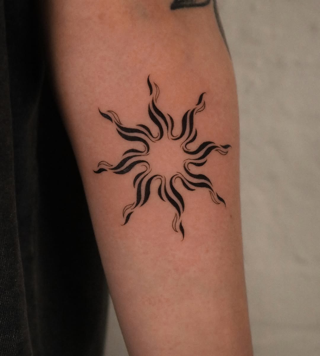 Stylish black sun tattoo with flowy lines