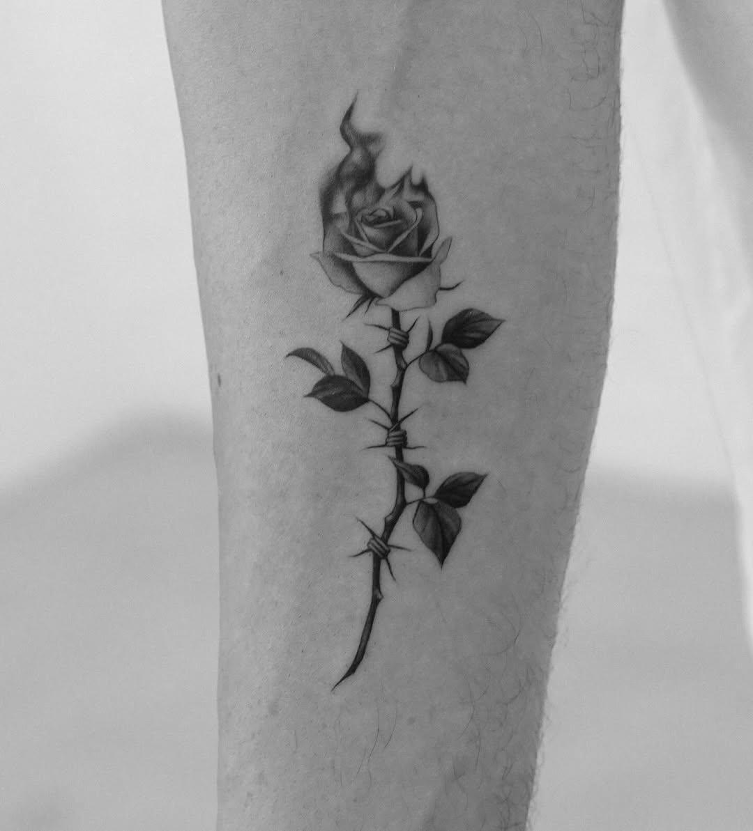 Elegant black rose tattoo with a fiery twist